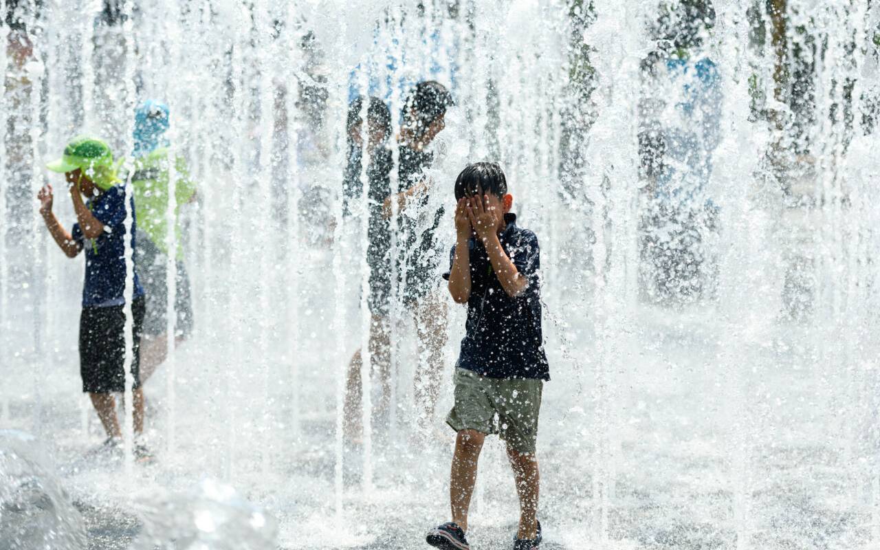 Kinder spielen an einem heißen Nachmittag in einem Springbrunnen auf dem Platz im Wasser.