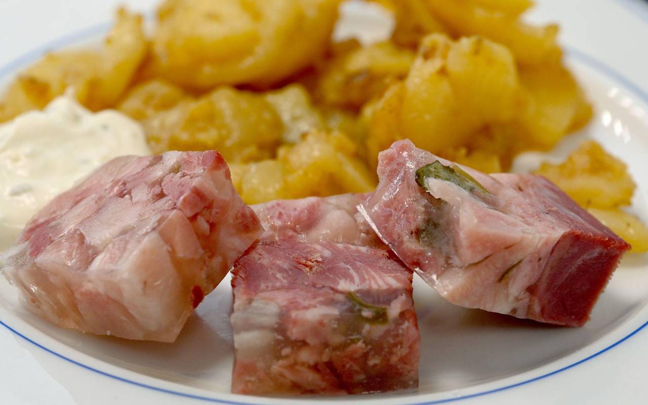 Sülze liegt auf einem Teller mit Bratkartoffeln