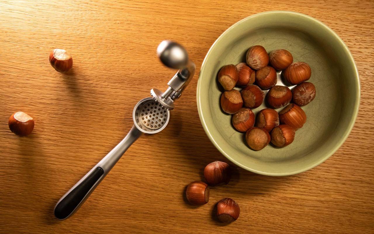 Haselnüsse liegen neben einer Knoblauchpresse