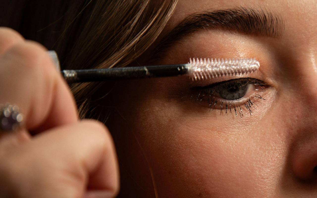 Frau tuscht sich die Wimpern mit Glitzer-Mascara