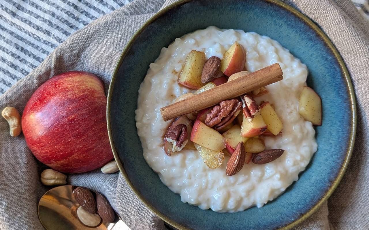 Milchreis mit Apfel, Zimt und Nüssen steht auf einem Tisch