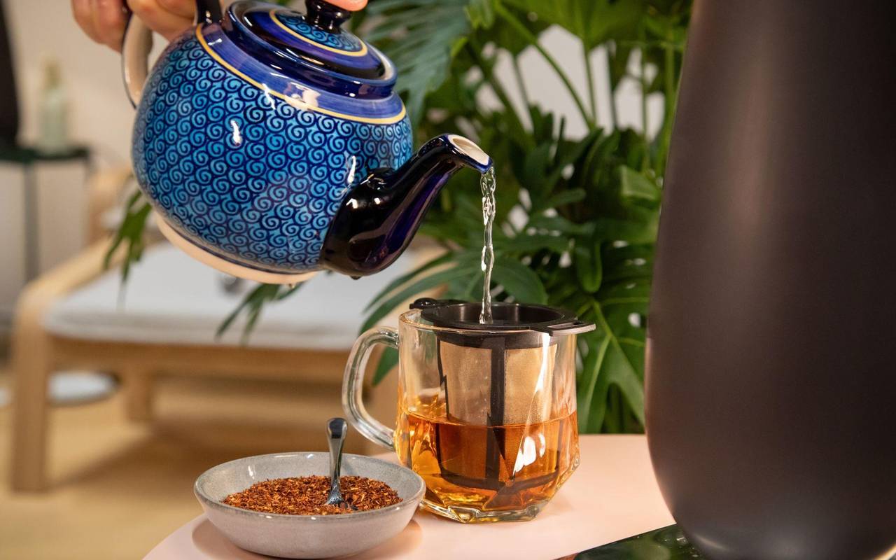 Ein Mann macht sich ein Glas Rooibos-Tee mit heißem Wasser