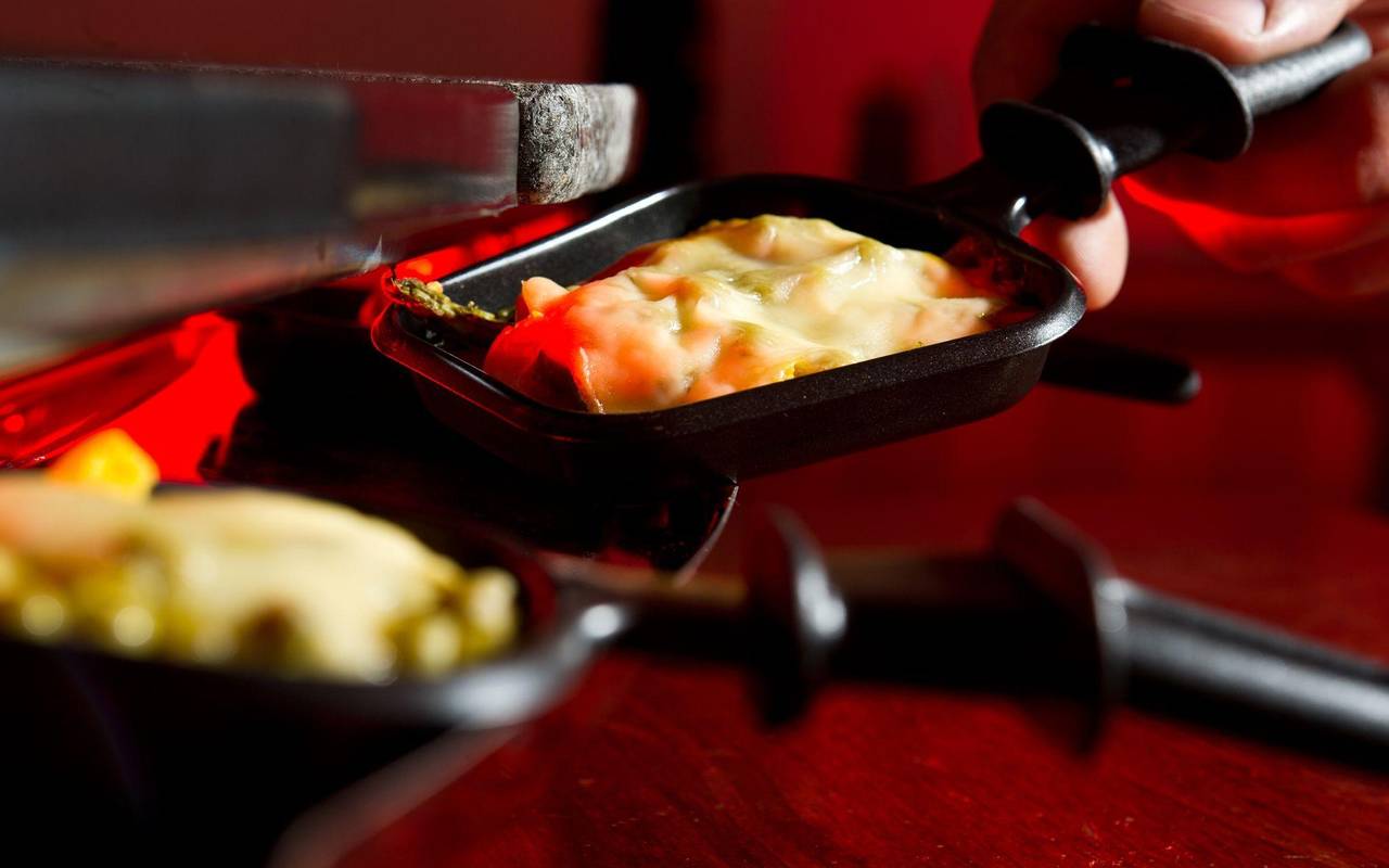Mann hält ein Raclette-Pfännchen in der Hand