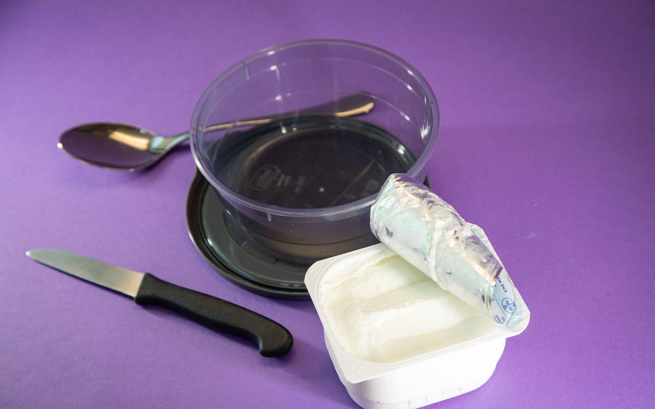 Ein Becher Quark steht neben einer Schüssel