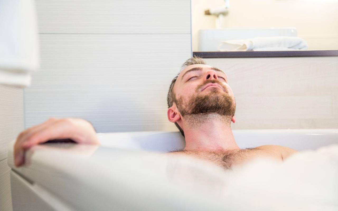 Ein Mann liegt mit geschlossenen Augen in der Badewanne