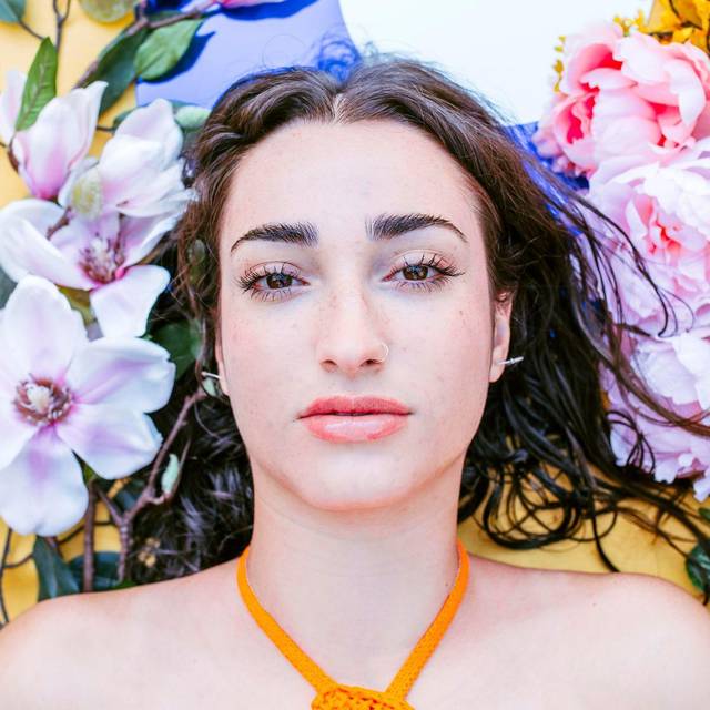 Natürlich geschminkte Frau liegt neben Blumen