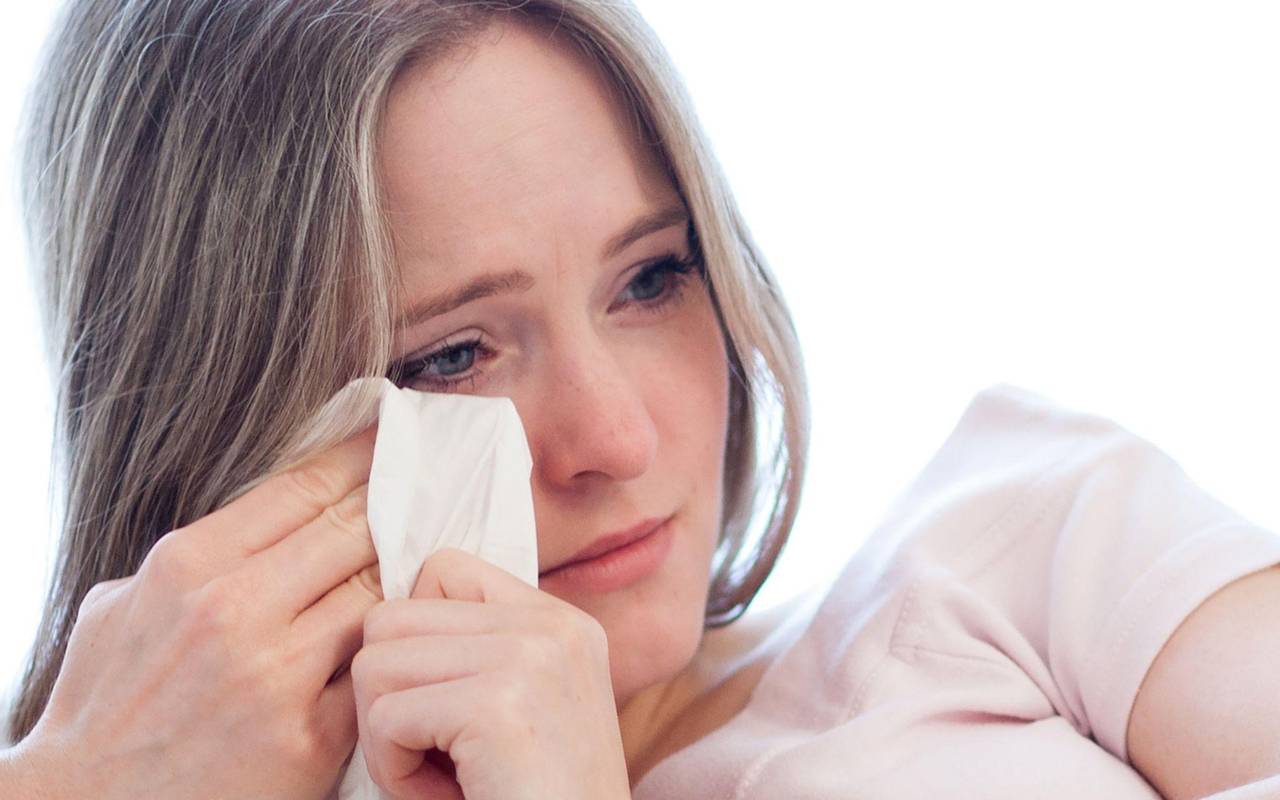 Frau wischt sich mit einem Taschentuch die Tränen aus den Augen